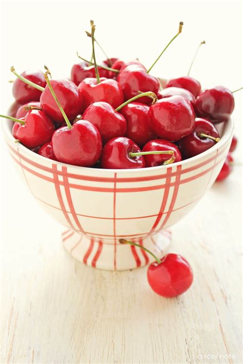 A Bowl Filled With Cherries On Top Of A Wooden Table
