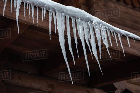 Closeup Photo Of The Icicles Hang From The Roof Of Wooden House Stock