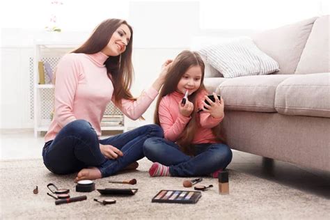 mother and daughter doing makeup sitting on the floor stock image everypixel