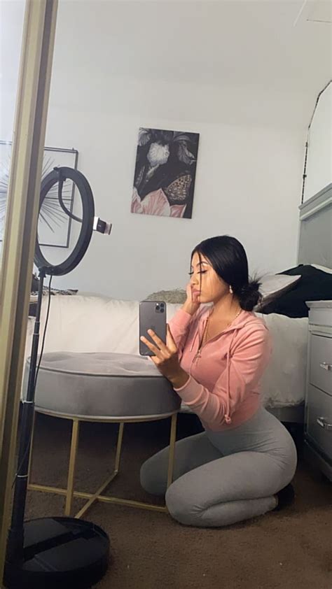 A Woman Squatting On The Floor In Front Of A Mirror Taking A Selfie