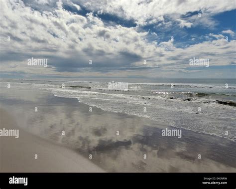 A Dramatic Cloudy Sky Reflected In Wet Sand As The Tide Goes Out Stock