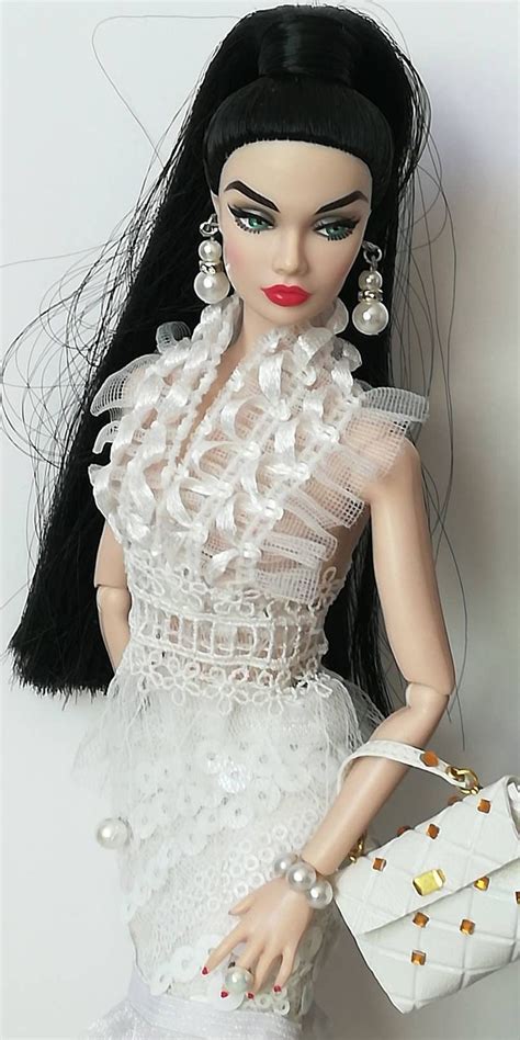 a doll with long black hair and white dress holding a handbag in her right hand