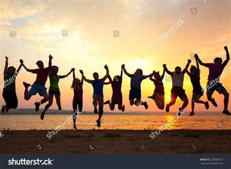 Group Of Happy Young People Jumping At The Beach On Beautiful Summer