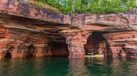 Kayaker Exploring Sandstone Sea Caves In Apostle Islands National