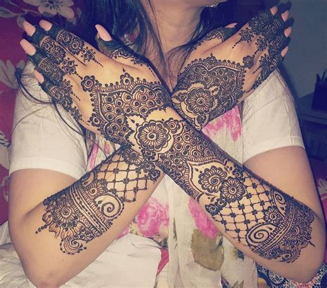 A Woman Is Holding Her Hands With Henna Tattoos On Their Arms And Both Palms