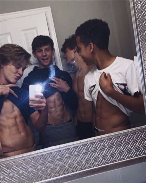 A Group Of Young Men Standing In Front Of A Mirror Looking At Their