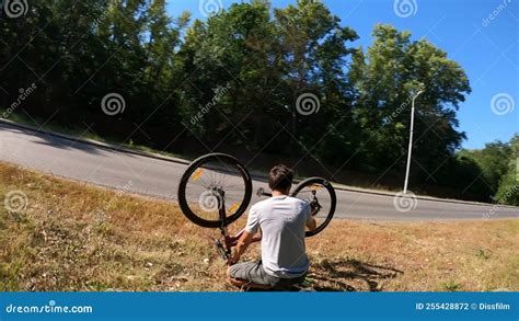 Circling Fpv Drone Shot Of Male Cyclist Checking Out Upside Down Bike On Side Of Road On Sunny