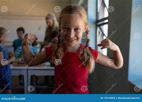 Schoolgirl Standing Flexing Her Bicep Muscles In An Elementary School