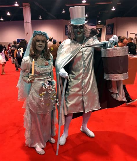 Two People Dressed In Costumes Standing On A Red Carpet