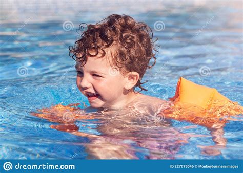 Young Boy In Outdoor Pool On Summer Vacation Learning To Swim With