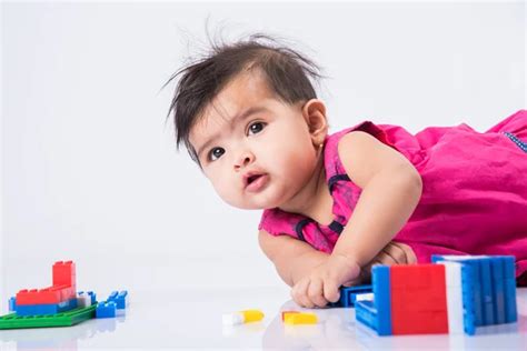 Indian Cute And Happy Baby Girl Playing With Toys Over Table Stock