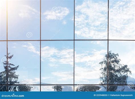 Sky Clouds And Tree Reflection In Grid Of Glass Window Of Modern