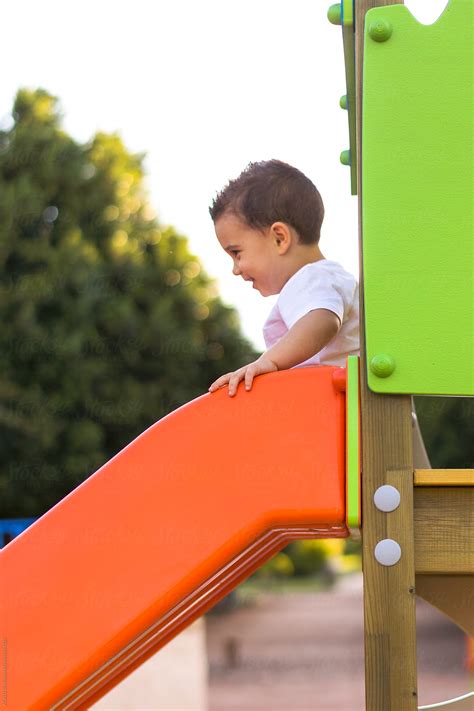 Child Sliding Down A Slide In A Playground By Stocksy Contributor