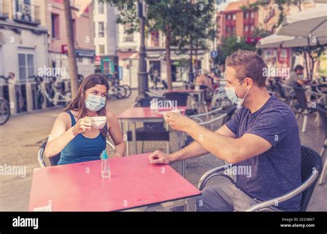 Couple Sitting In A Coffee Shop Wearing Surgical Protective Face Mask