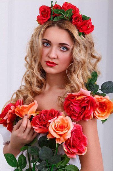 A Woman With Flowers In Her Hair Is Holding A Bouquet Of Red And Orange Roses