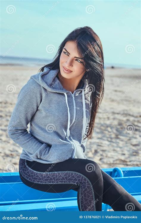 A Beautiful Girl With Tanned Skin Wearing A Gray Hoodie Looking Away And Holds Hands In Pockets