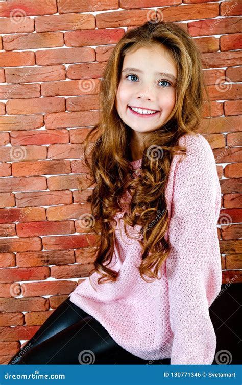 Portrait Of Adorable Smiling Sitting Little Girl Child Stock Photo