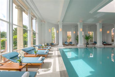 A Large Indoor Swimming Pool With Sun Loungers And Tables Next To It