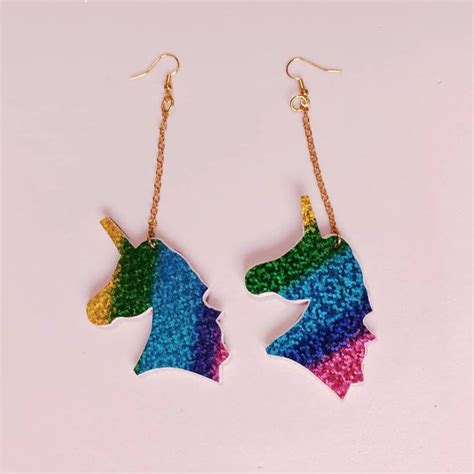 A Pair Of Unicorn Earrings With Chains Hanging From Them