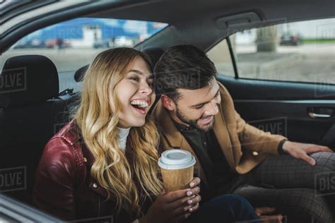 Happy Young Couple Laughing While Sitting Together In Taxi Stock