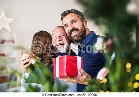A Small Girl With Father And Grandfather Exchanging Presents At