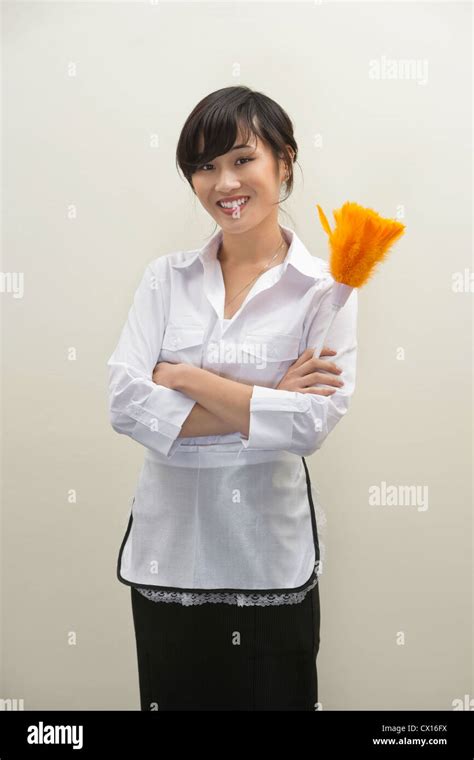 Portrait Of Female Housekeeper Holding Feather Duster Against Gray