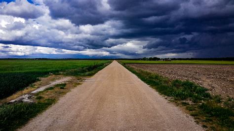 Dirt Road Surrounded With Green Field Under Cloudy Sky · Free Stock Photo