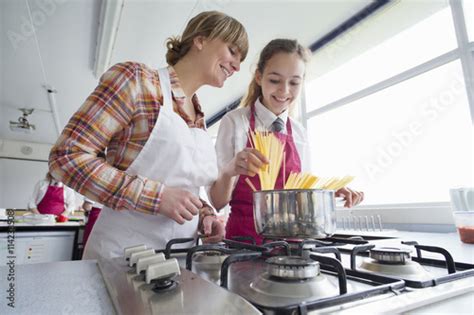 Teacher Teaching High School Student Cooking Pasta In Home Economics