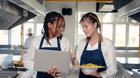 Two African And Asian Students Stand In A Cooking Class On Campus