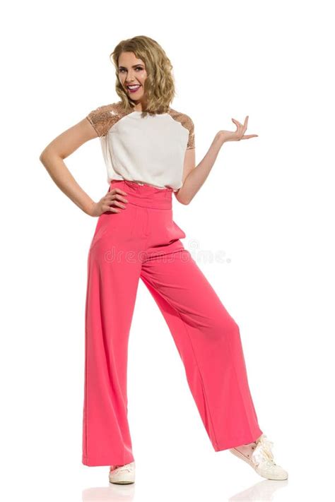 woman in pink wide legs trousers is standing pointing and smiling stock image image of palm