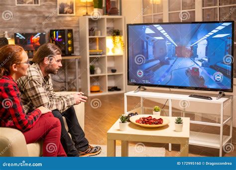 Couple Playing Video Games On Big Screen Tv In The Living Room Late At