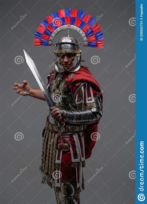 Proud Roman Soldier Posing Against Gray Background Holding Sword Stock