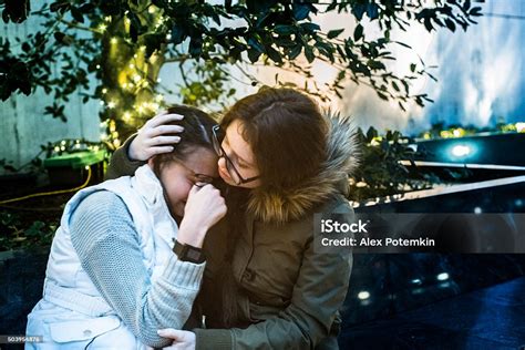 Teenager Girl Crying And Other Sister Comforting Her Stock Photo
