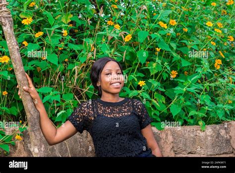 Beautiful Black Girl Standing Near A Fence With Tree Marigold