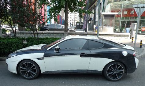 The tuscani wears a circular badge containing a smaller circle of black and grey horizontal bars which is overlaid with a letter 't' painted gold on the left and silver on the right. Hyundai Tiburon in black & white in China - CarNewsChina.com