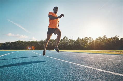 Athlete In Mid Air While Sprinting Down A Running Track Stock Photo