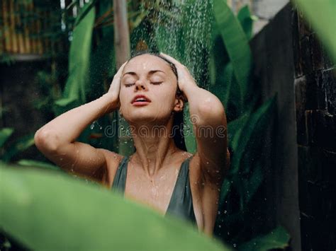 A Woman Takes A Shower And Washes Her Head And Hair Outdoors Against