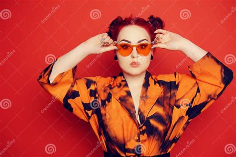 cute girl on a red background red hair and tunnels in the ears red dress and lips anime poses