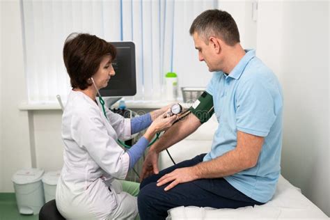 Female Doctor Measures Blood Pressure With A Sphygmomanometer To Male