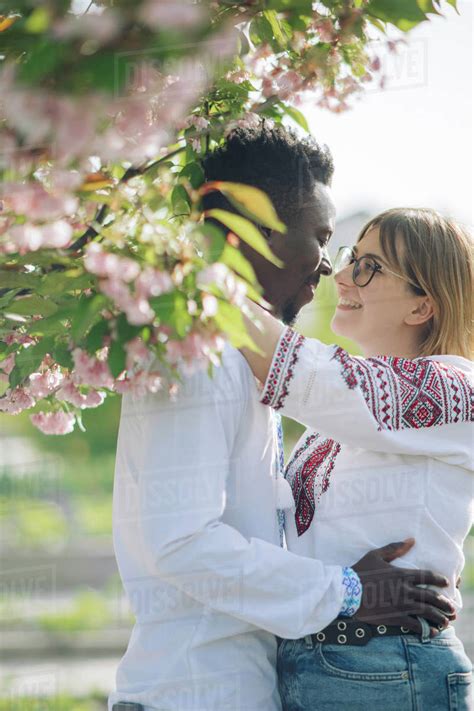 Interracial Couple Embraces In Spring Garden Dressed In Ukrainian Traditional Ethnic Embroidered