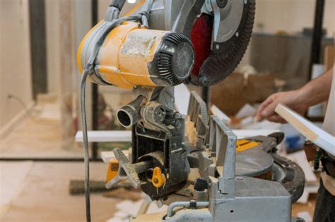 Installing baseboards in your home is a relatively straightforward way to spruce the place up a bit. Worker cuts the wood moldings baseboard on the miter saw ...