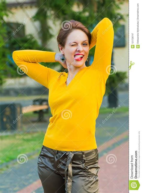 grimacing smiling attractive girl with short hair in bright yellow blouse outdoor stock image