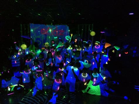 A Group Of People Standing Next To Each Other In Front Of A Neon Light Wall