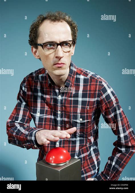 A Nerdy Guy With His Hand Poised Above A Red Game Show Buzzer Stock