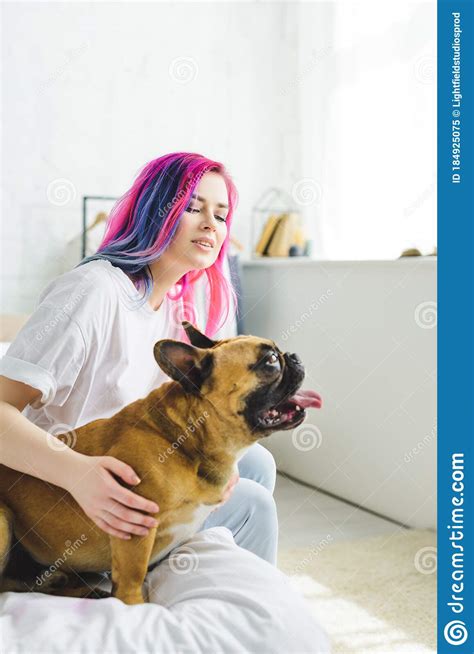 Girl With Colorful Hair Petting Bulldog Looking Away While Sitting