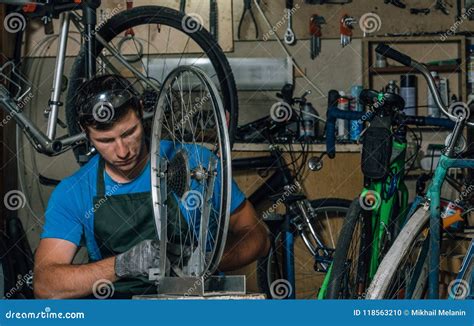 Competent Bicycle Mechanic In A Workshop Repairs A Bike Stock Photo