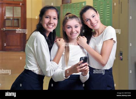Three Happy High School Girls Have Fun With Their Cell Phone Stock