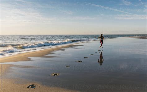 Fit Female Athlete Making Footprints While Running On Beach By Stocksy Contributor Raymond