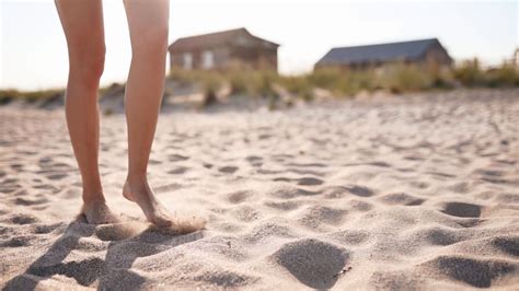 Close View Of Tanned Woman Legs And Feet Walking On Sandy Beach To The