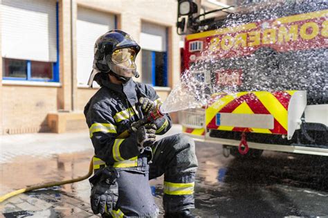 Firefighter Pouring Water To Extinguish A Fire Stock Photo